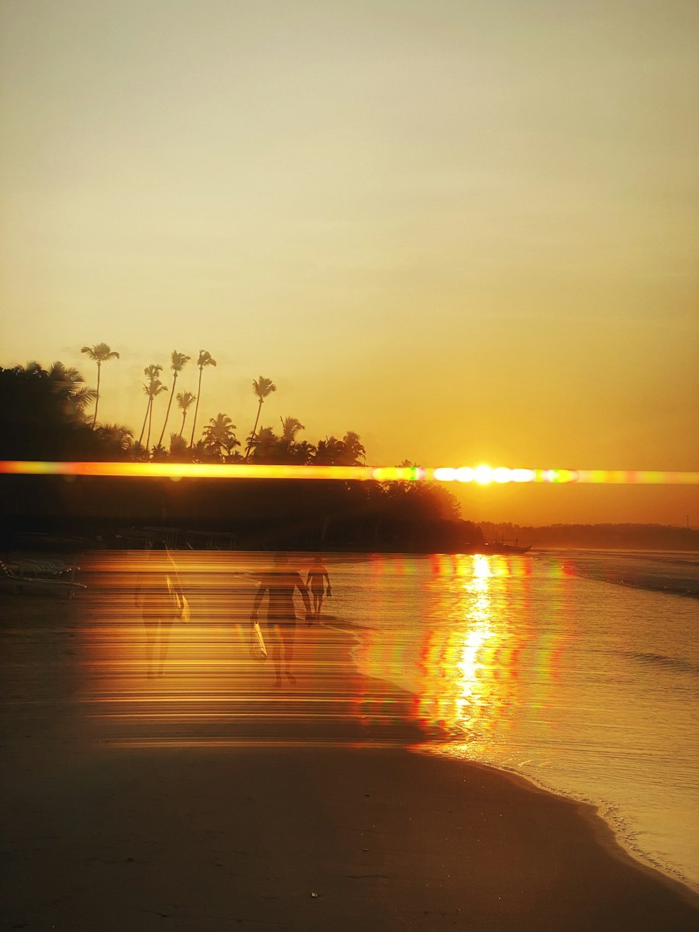 a group of people walking along a beach at sunset