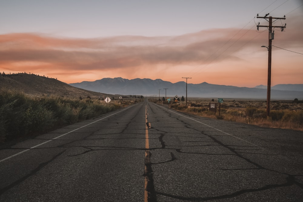 a long empty road with mountains in the background