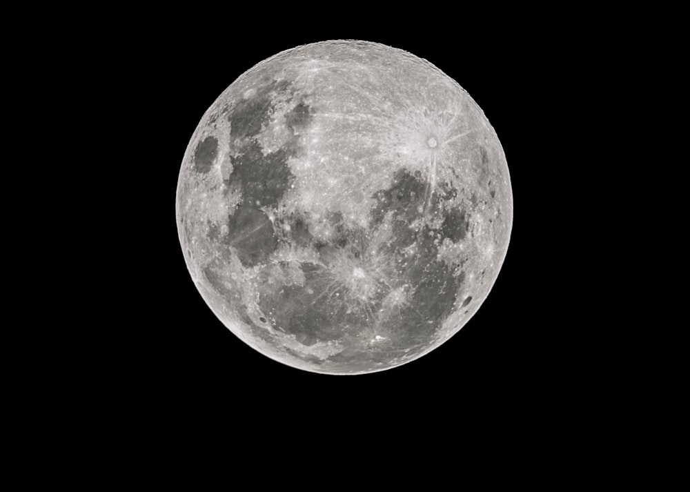 a full moon is seen in the dark sky