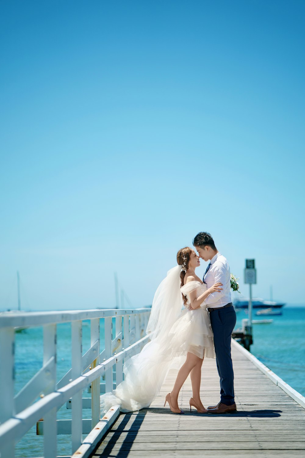 a bride and groom kissing on a pier