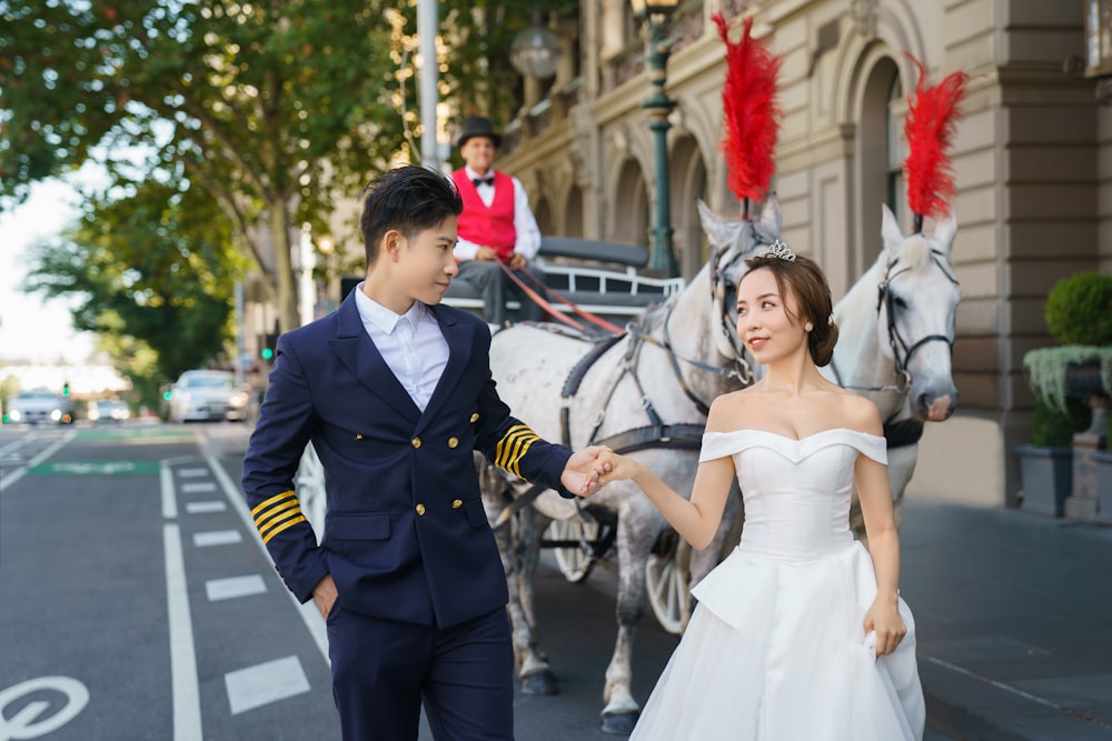 a man and a woman in a wedding dress walking a horse drawn carriage down a