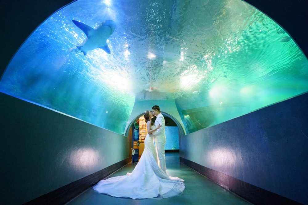 a bride and groom standing in a tunnel under water