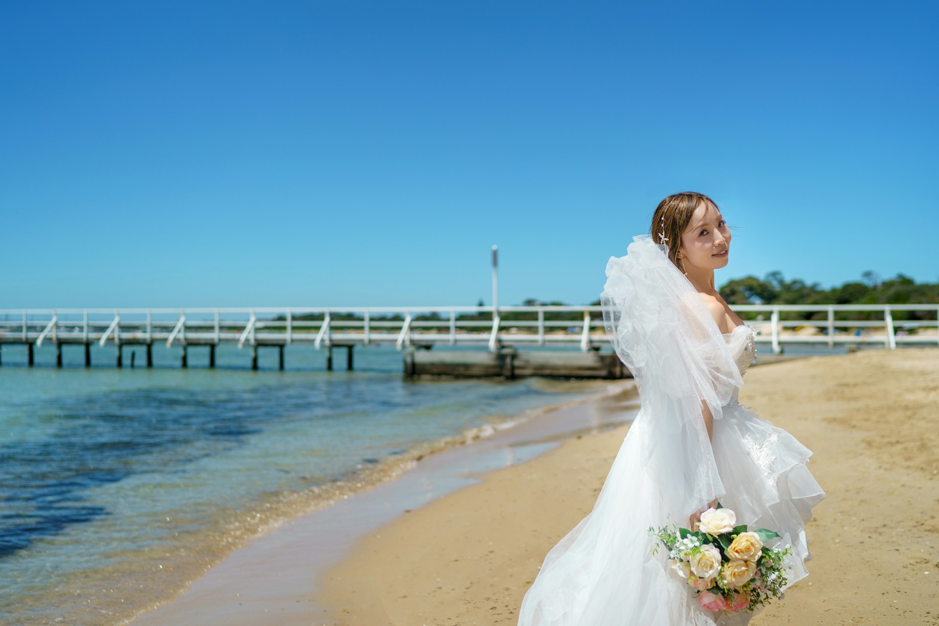 a woman in a wedding dress standing on a beach