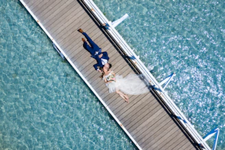 a bride and groom laying on a dock