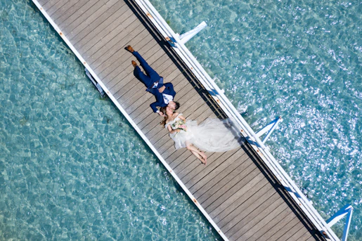 a bride and groom laying on a dock