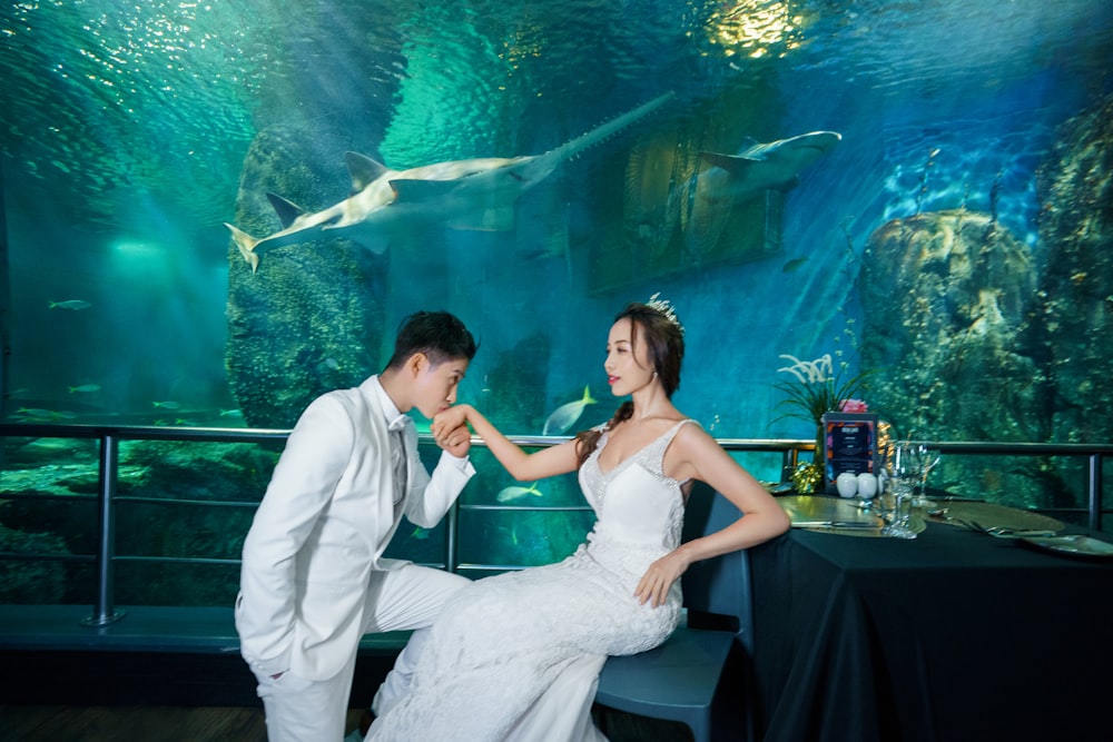 a bride and groom dancing in front of a large aquarium