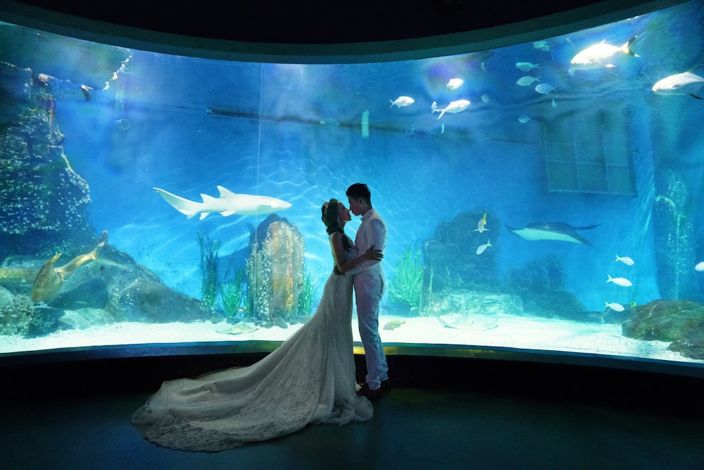 a bride and groom standing in front of an aquarium