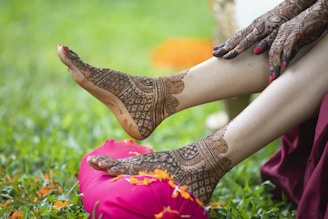 a woman's feet with henna on sitting on a pink pillow