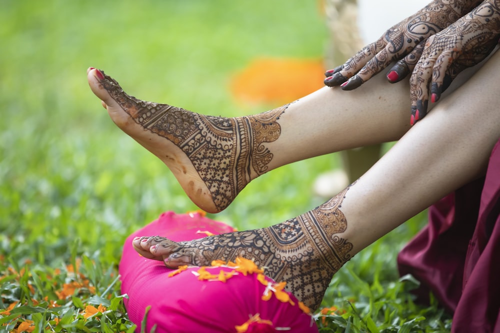 a woman's feet with henna on sitting on a pink pillow