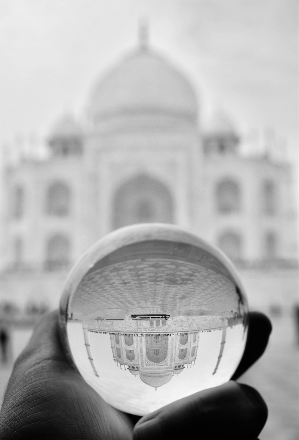 a person holding up a glass ball in front of a building