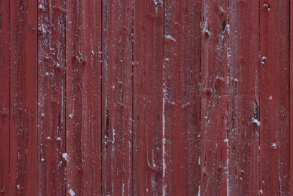 a red wooden fence with snow on it