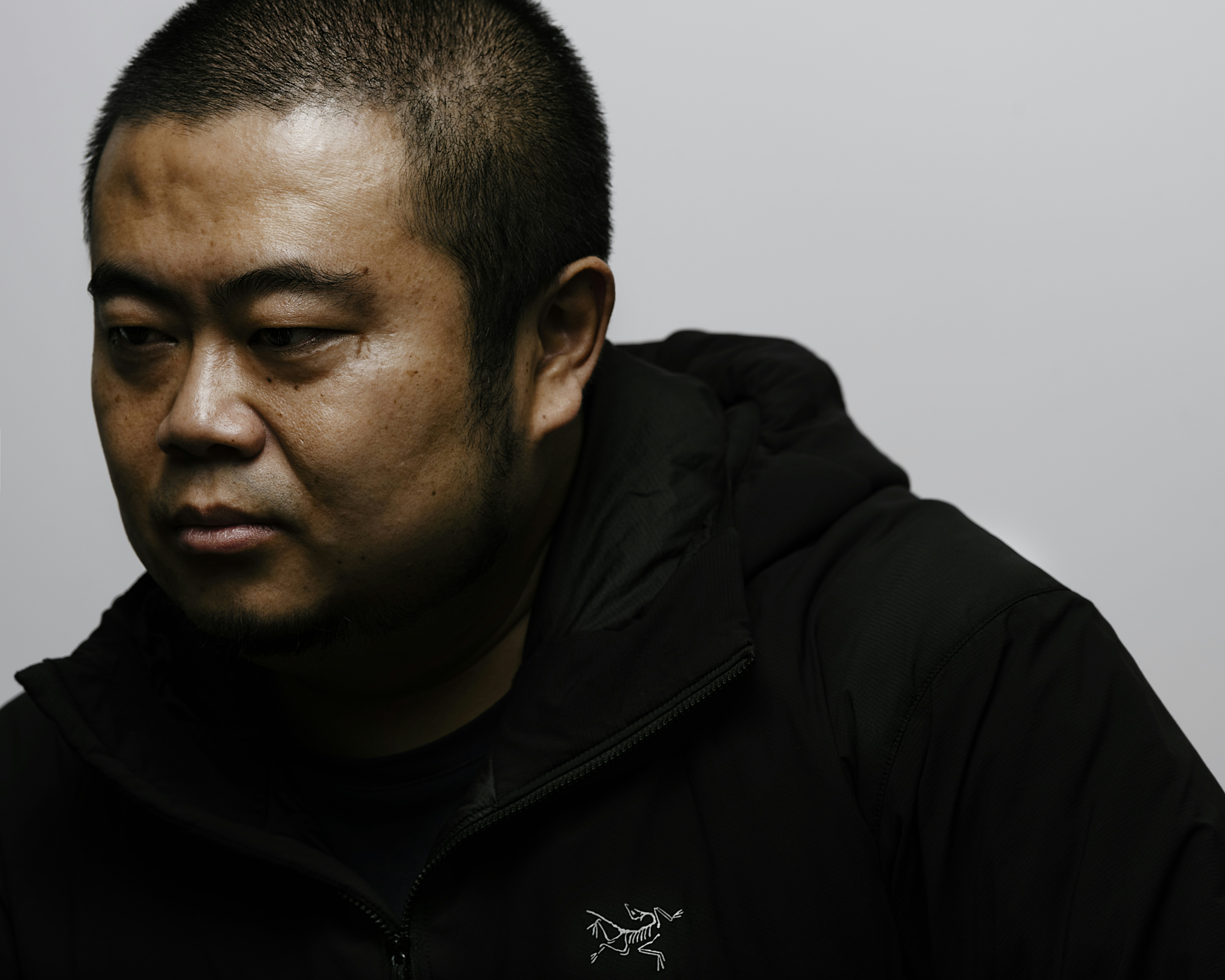 a man in a black hoodie stares at the camera