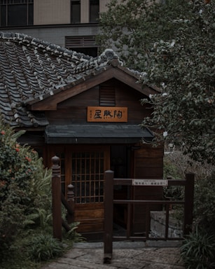 A serene Japanese-style wooden house entrance surrounded by seasonal greenery.