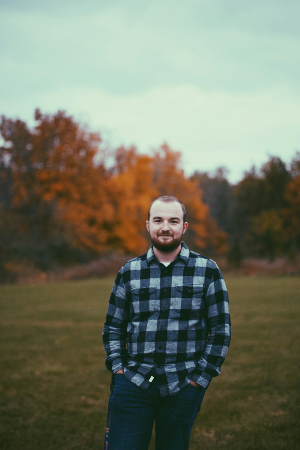 a man standing in a field with trees in the background