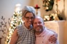 a man and a woman pose for a picture in front of a christmas tree