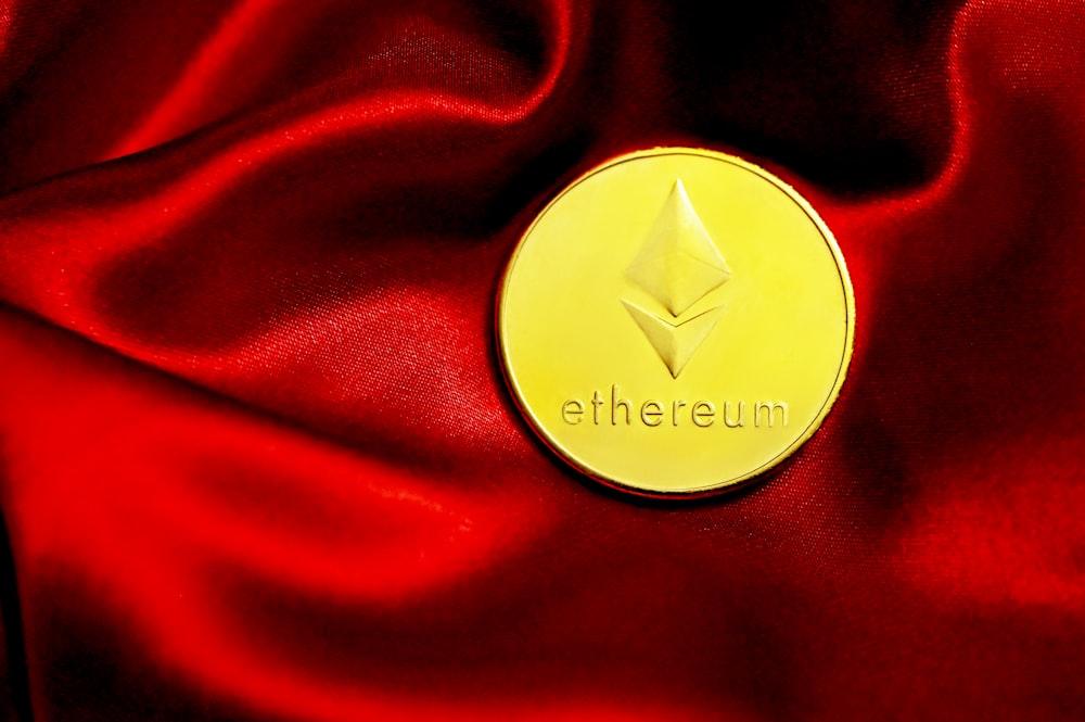 a close up of a red cloth with a gold coin