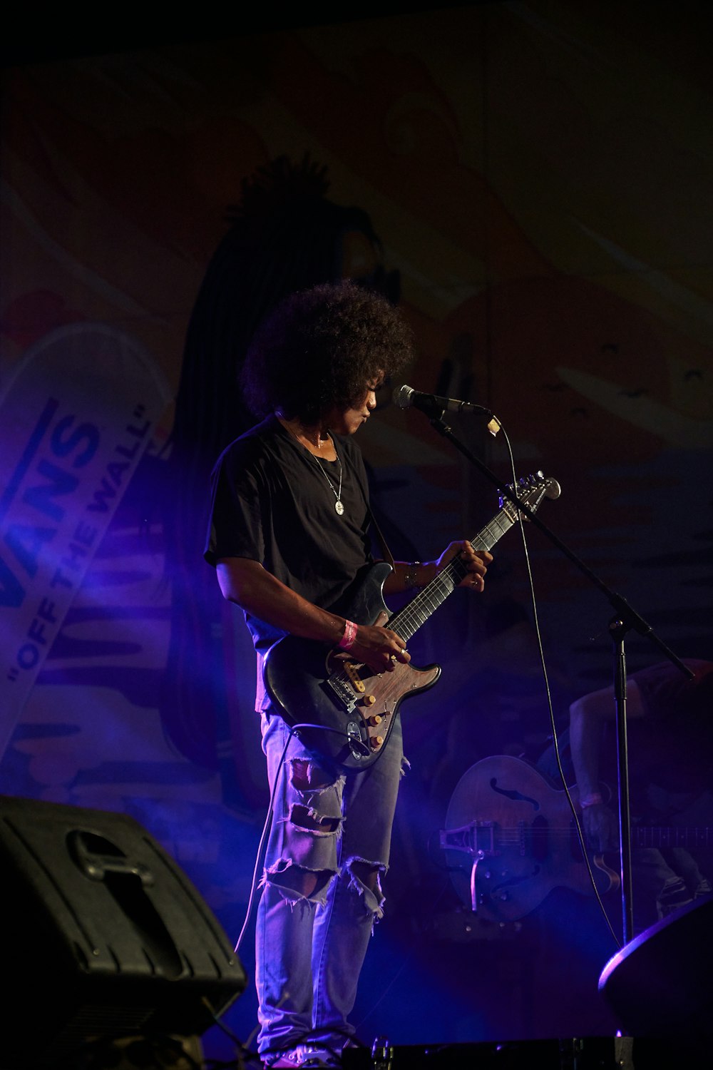 a man standing on a stage playing a guitar