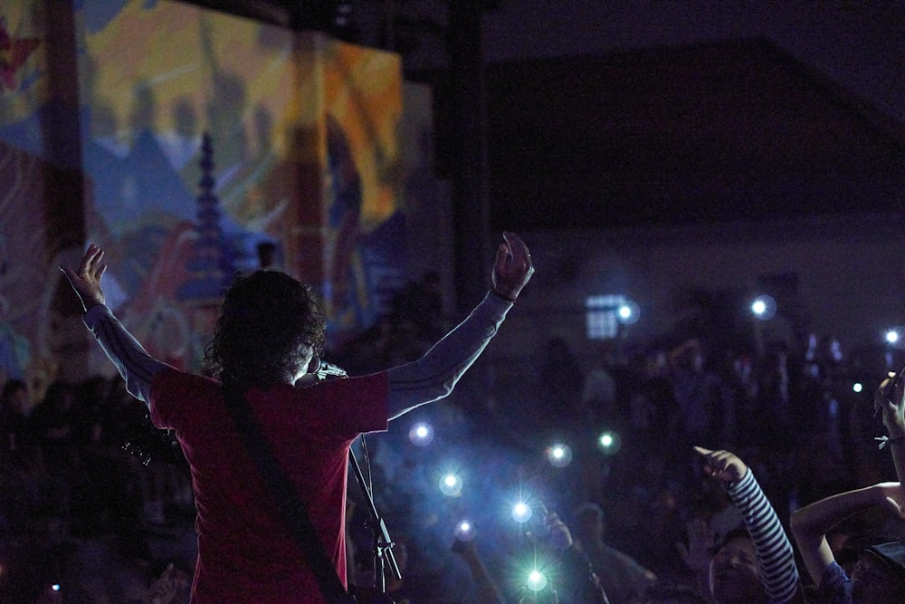 a woman standing in front of a crowd holding her arms up