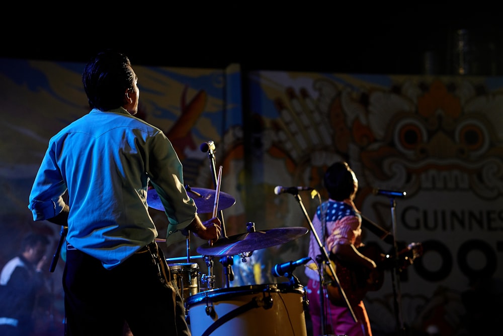 a man playing drums while another man plays the drums