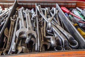 Heavy-duty wrench lying next to a toolbox filled with various hand tools.