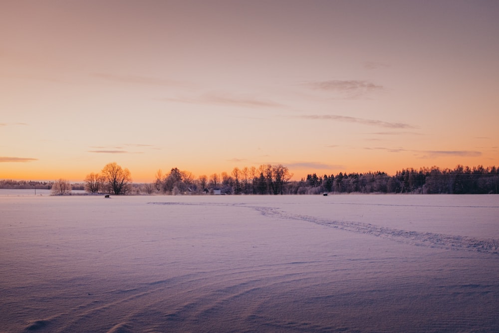 a sunset over a snow covered field