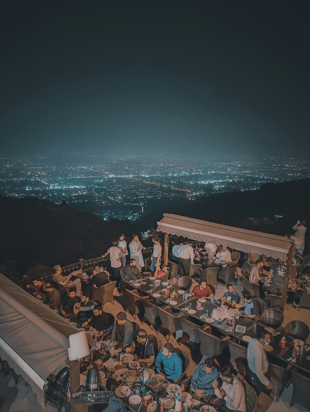 a group of people sitting around a table on top of a hill