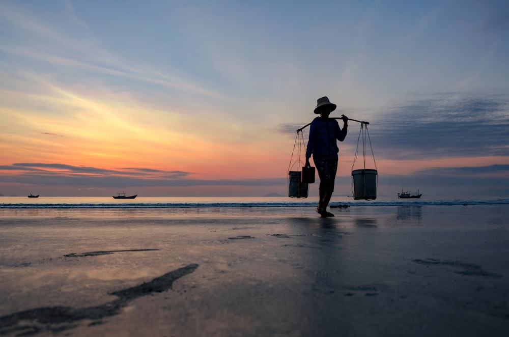 a person walking on a beach carrying buckets