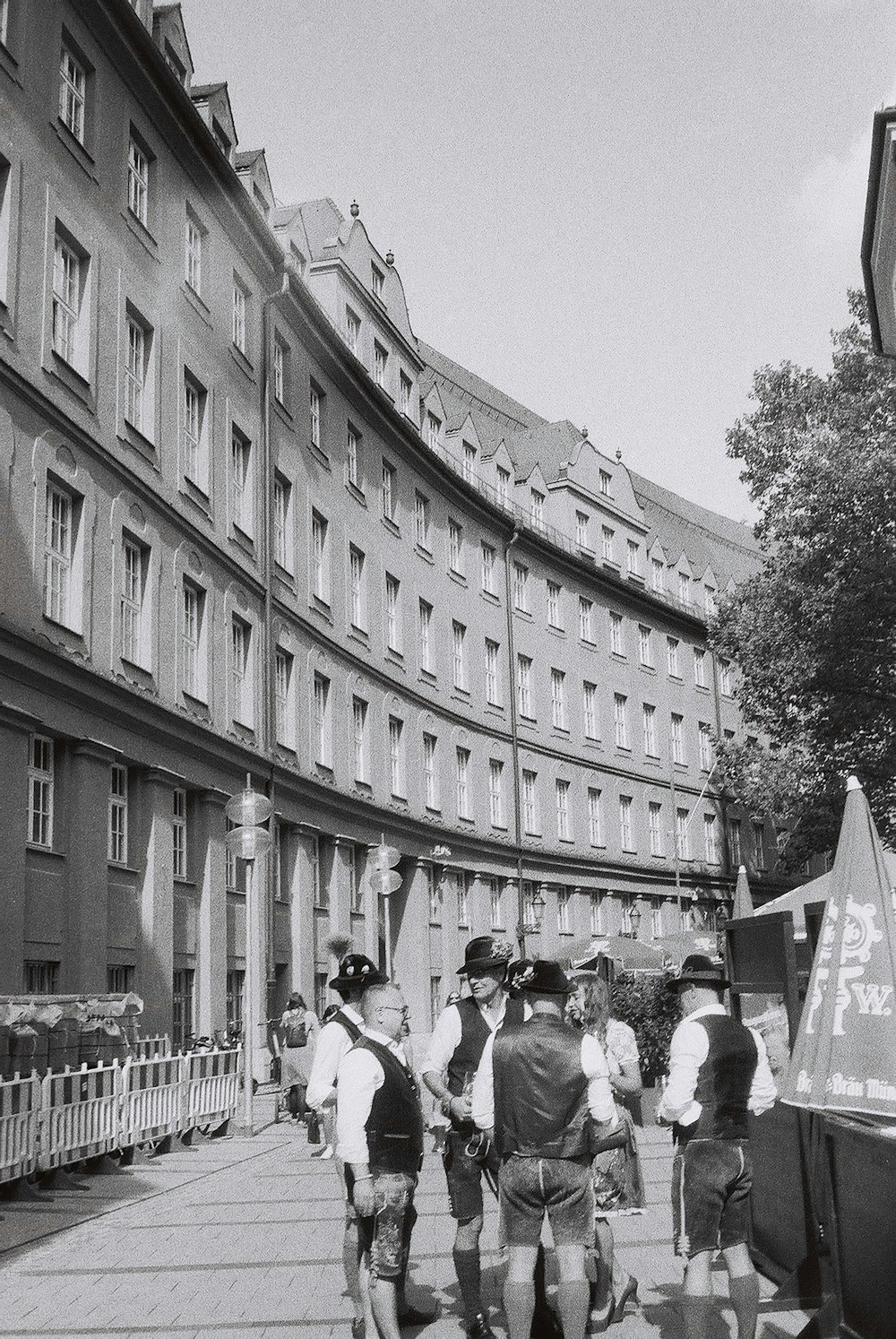 a group of men walking down a street next to tall buildings