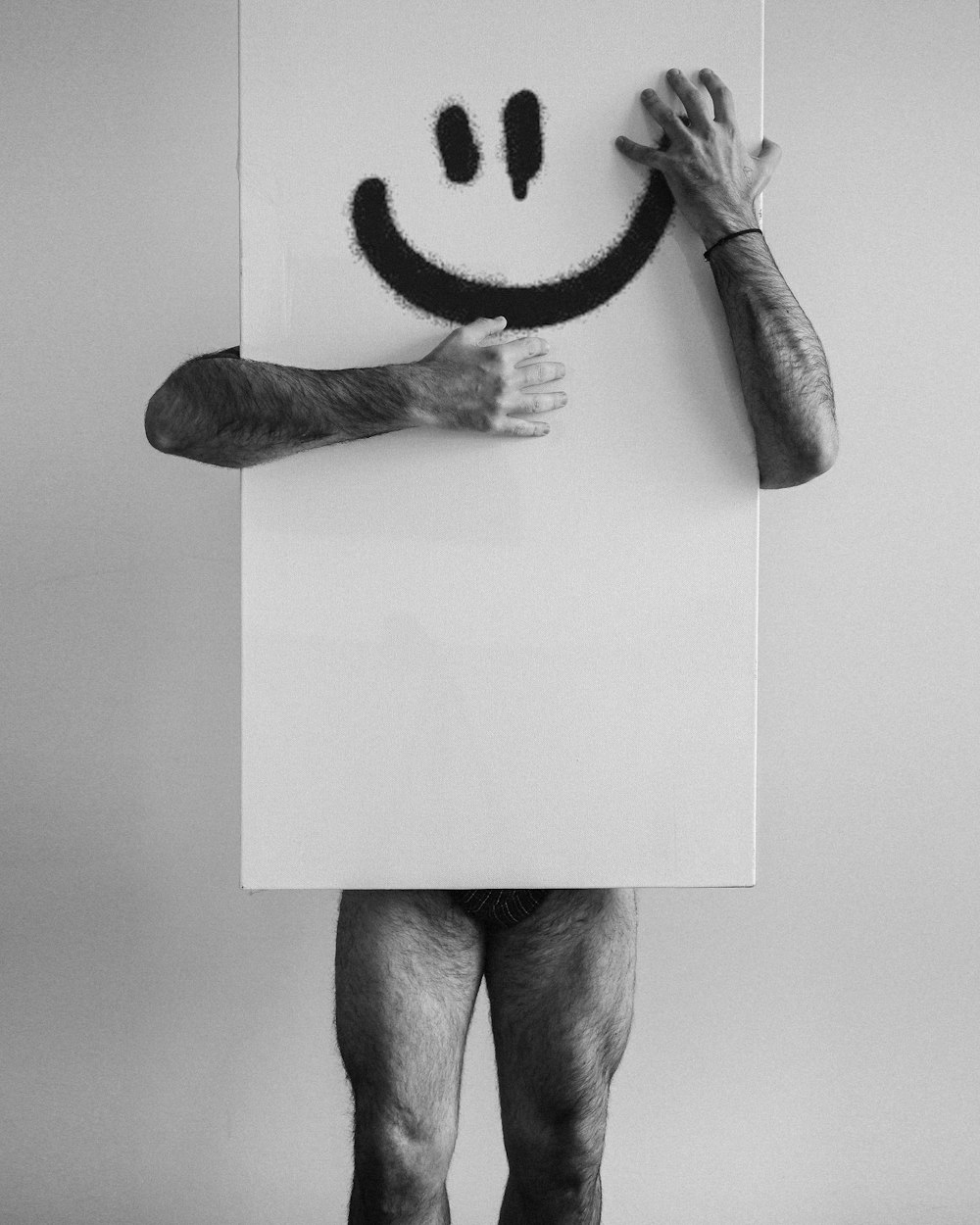 Un hombre sosteniendo un cartel con una cara sonriente dibujada en él