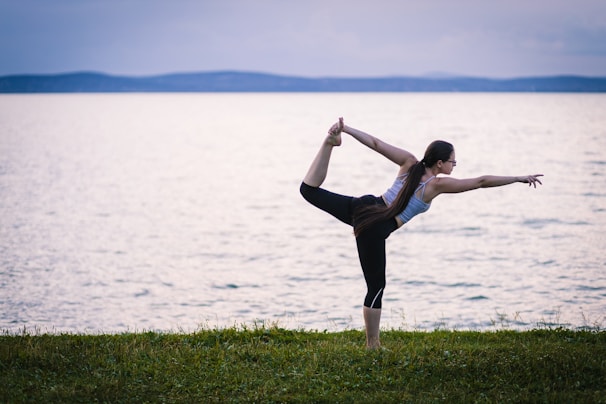 a woman doing a yoga pose by the water