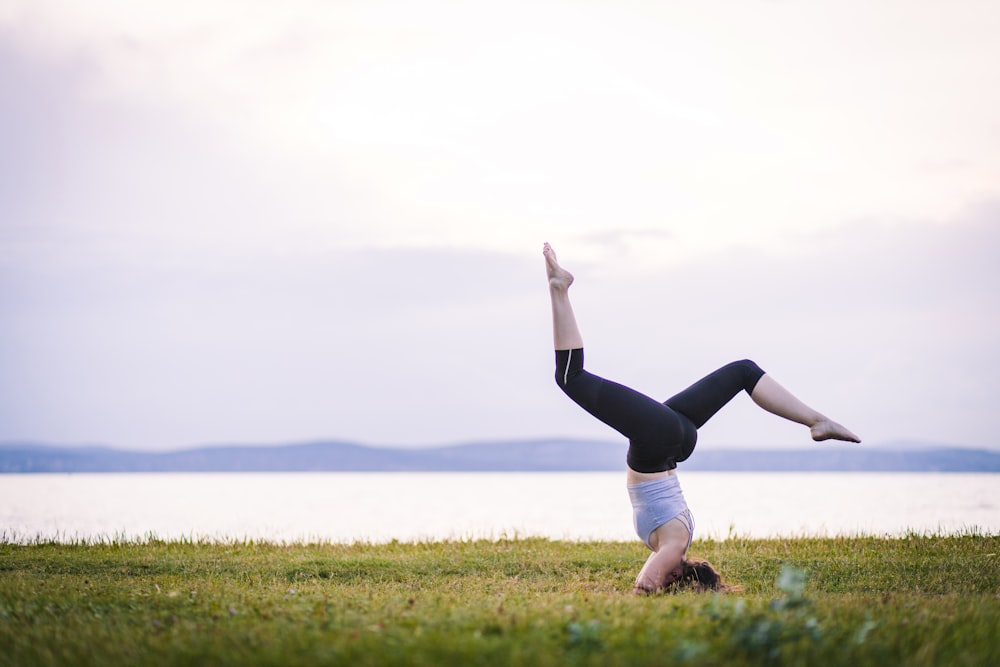 a woman doing a handstand in a field