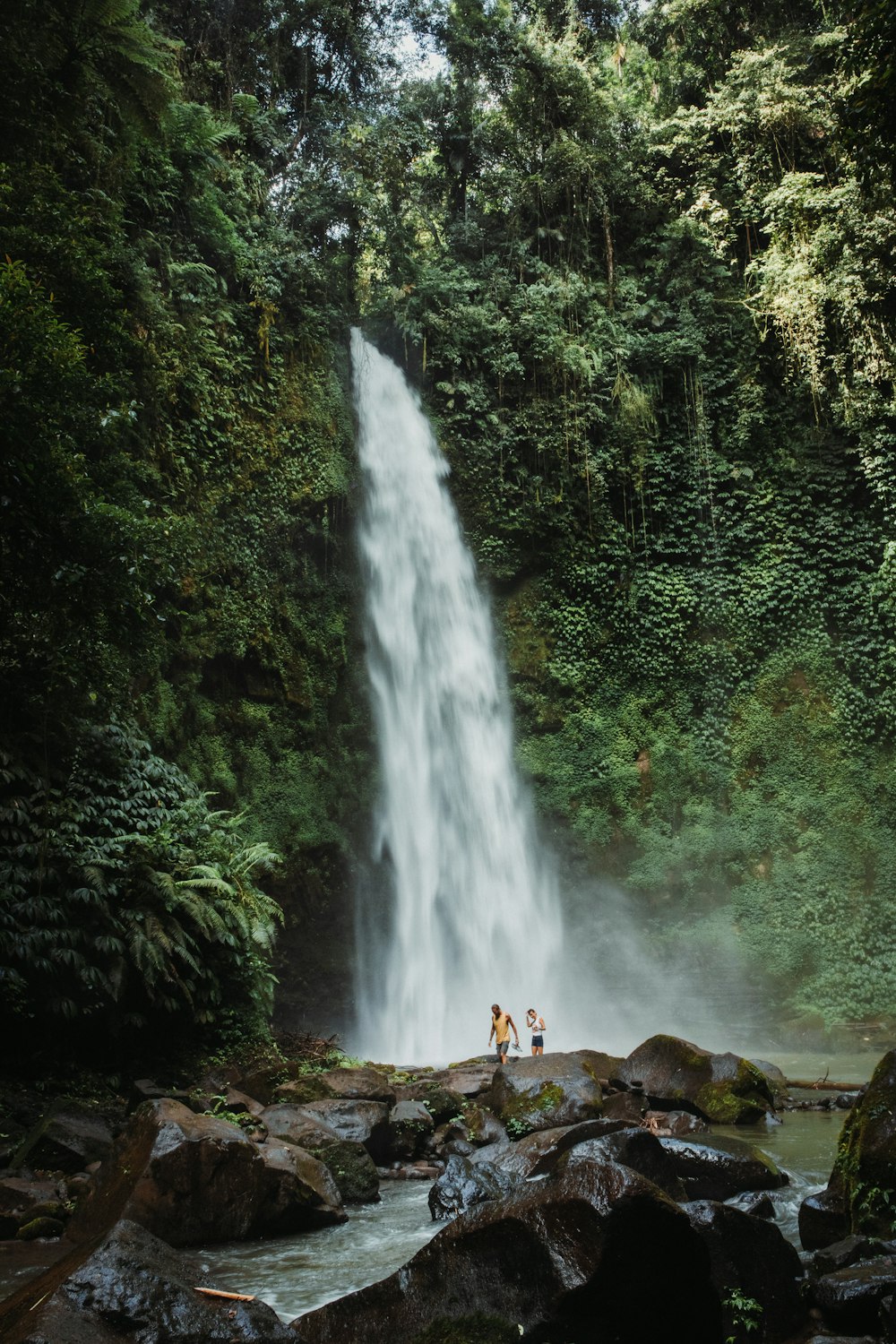 two people standing in front of a waterfall