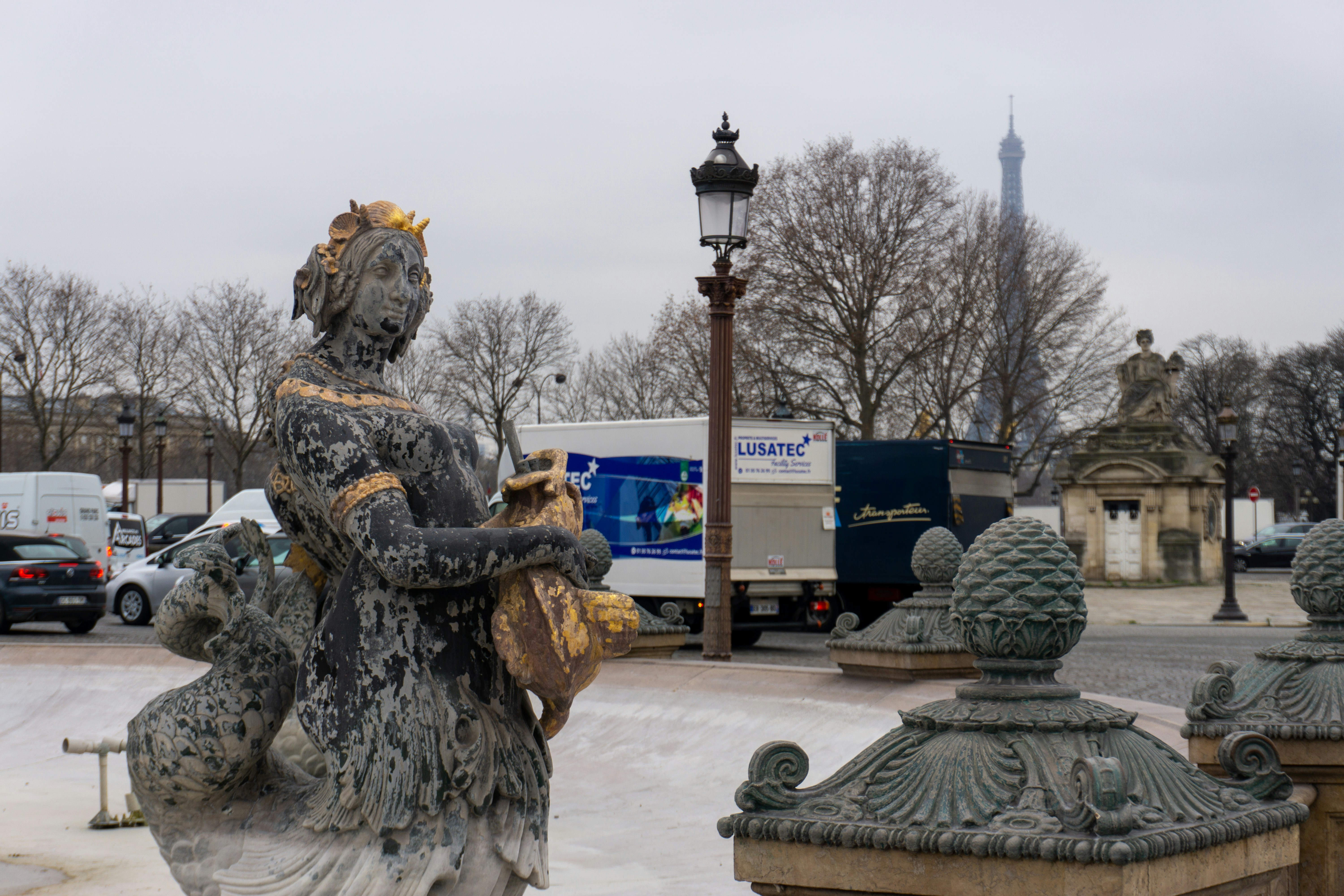 a statue of a woman holding a bird next to a lamp post