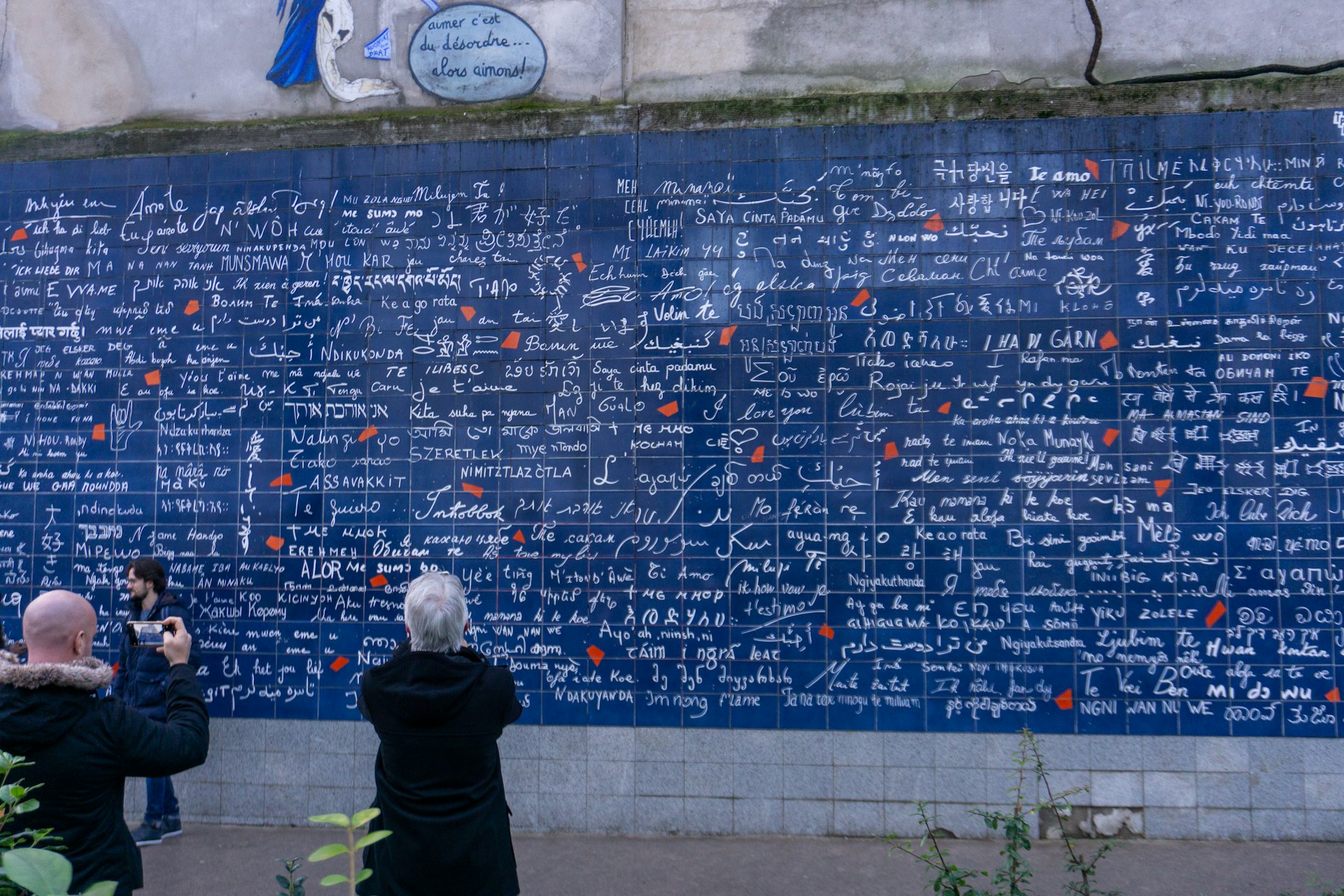 a group of people standing in front of a blue wall with writing on it
