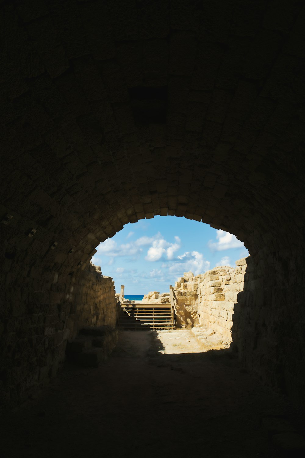 a tunnel in a stone wall leading to the ocean