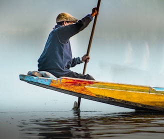 a person sitting on a yellow boat with a paddle