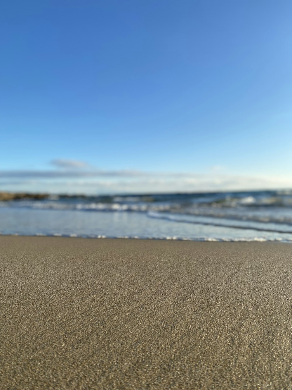 Ein Sandstrand direkt am Meer unter blauem Himmel