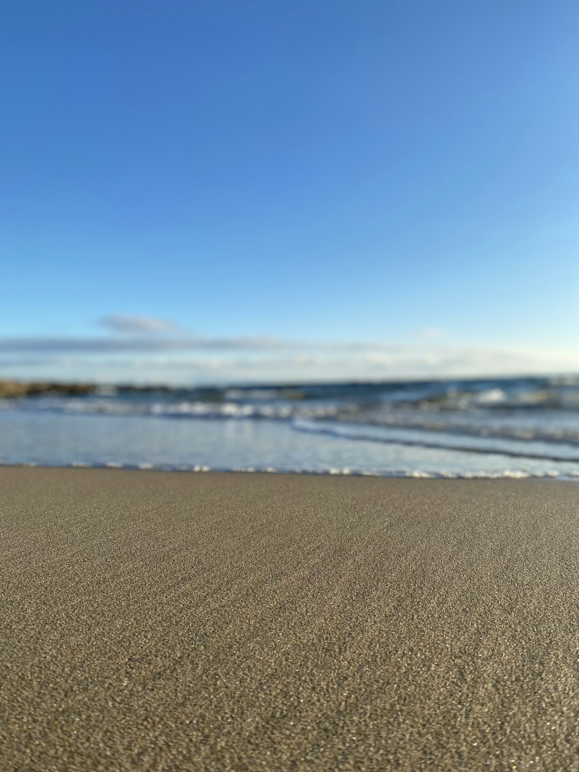 a sandy beach next to the ocean under a blue sky