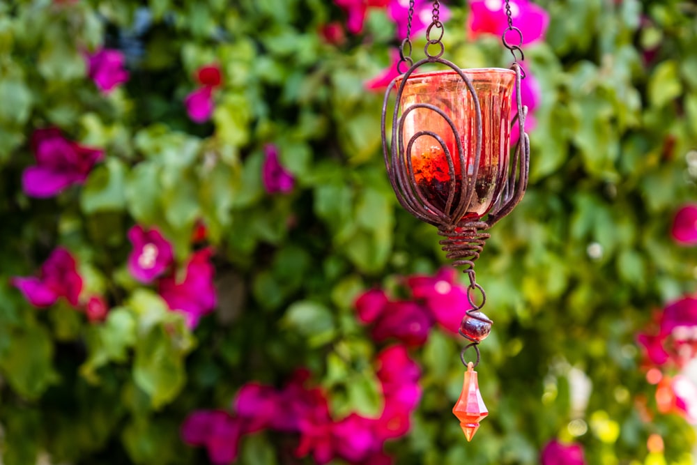 a glass hanging from a chain in front of flowers