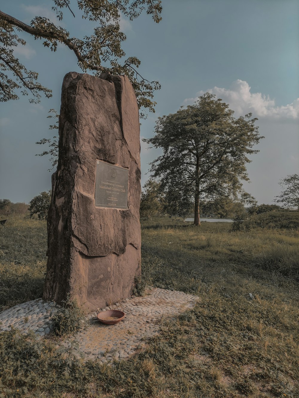 a large rock with a plaque on it in a field