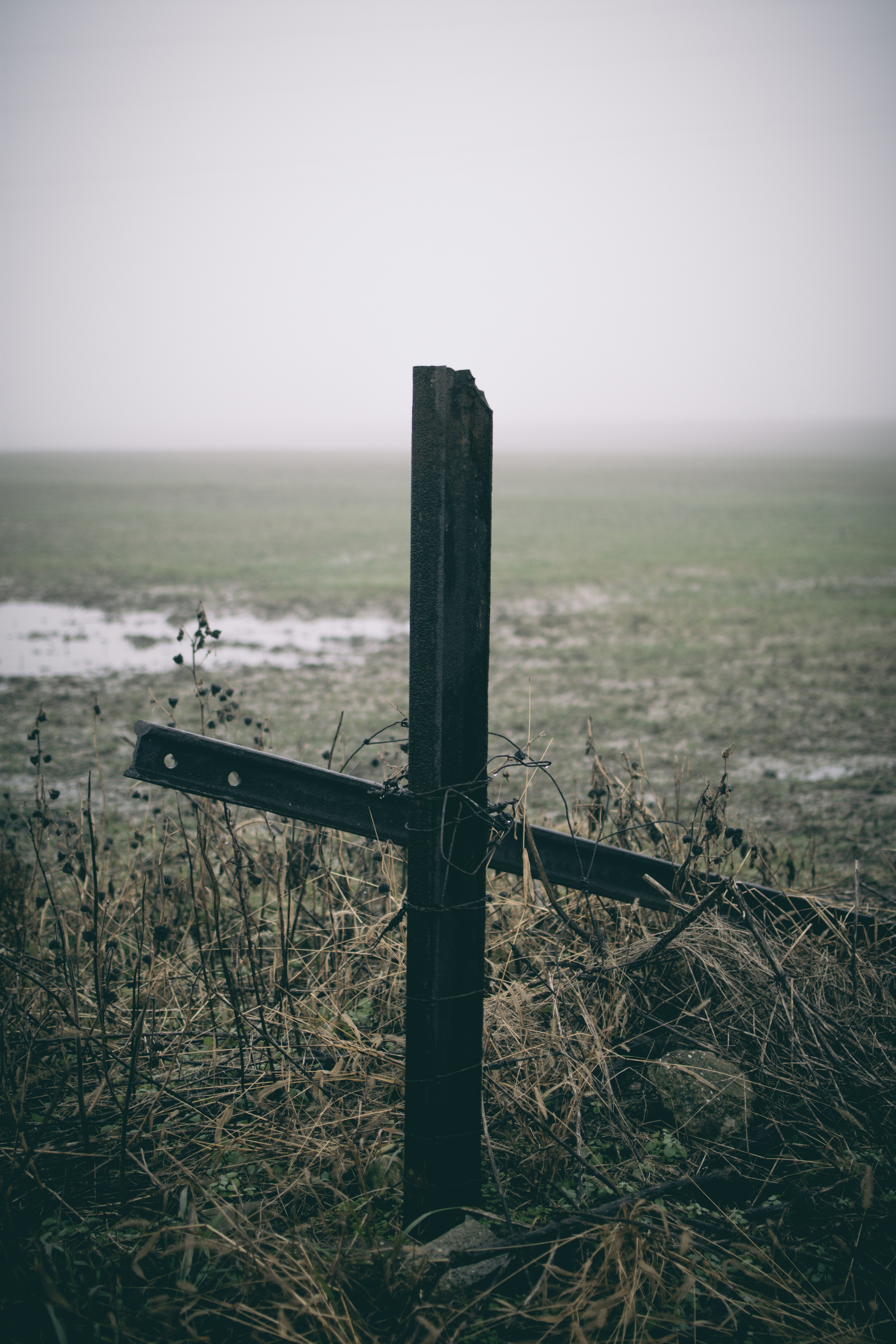 a wooden cross sitting on top of a grass covered field