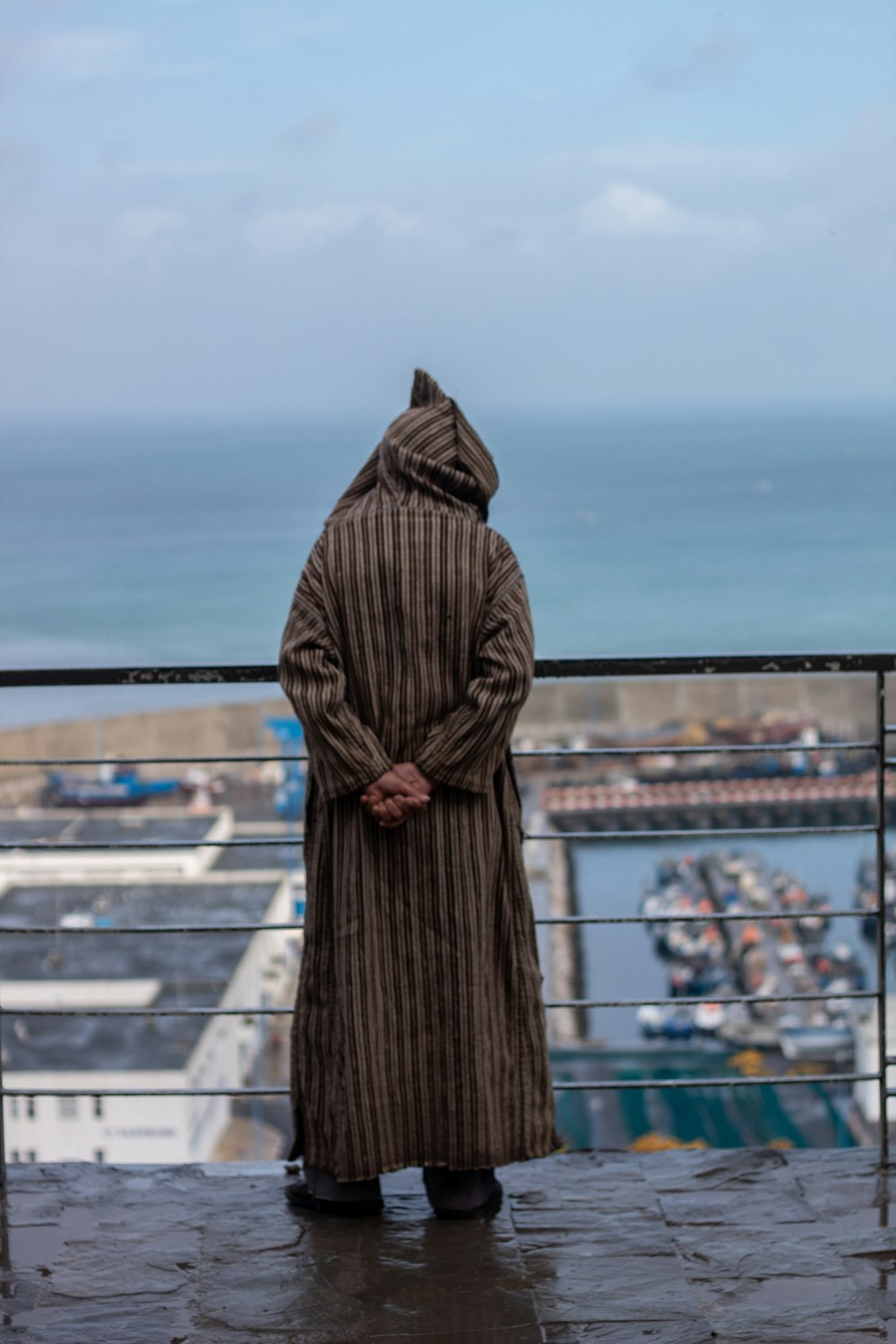 a person in a long coat standing on a balcony