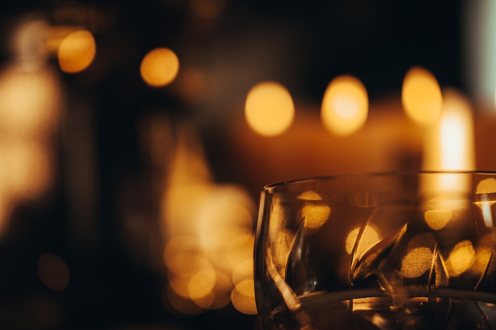 a close up of a wine glass with candles in the background