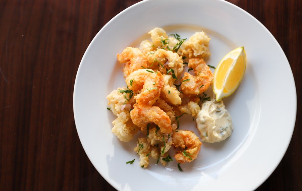 a white plate topped with shrimp and a lemon wedge