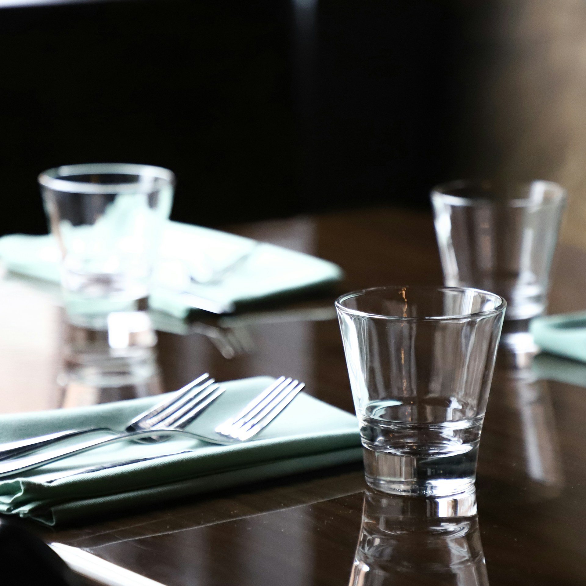 a wooden table topped with glasses and silverware