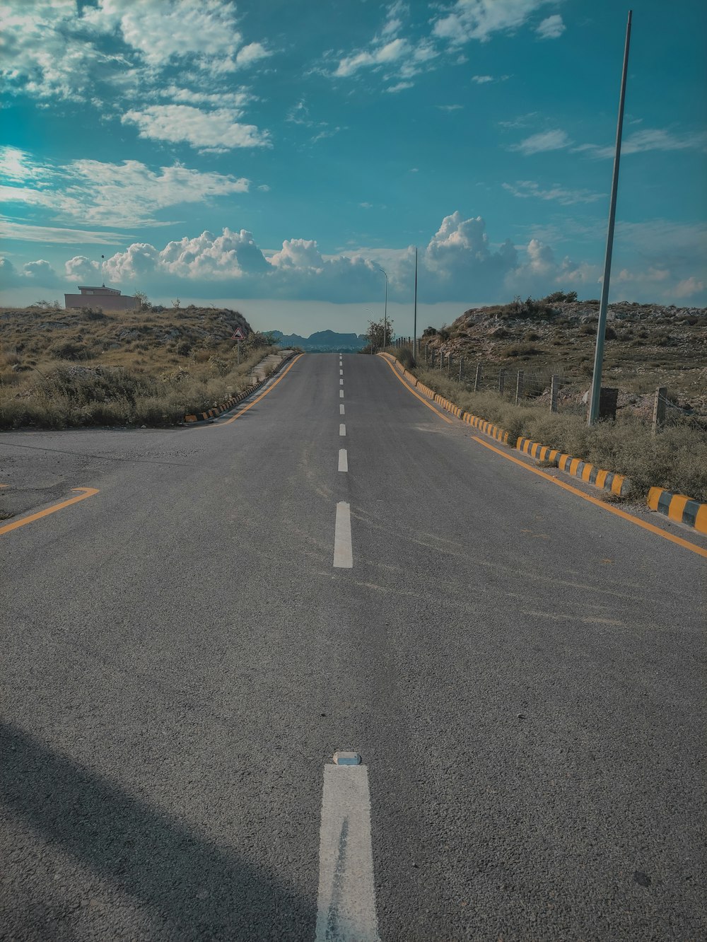 a long empty road with a blue sky in the background