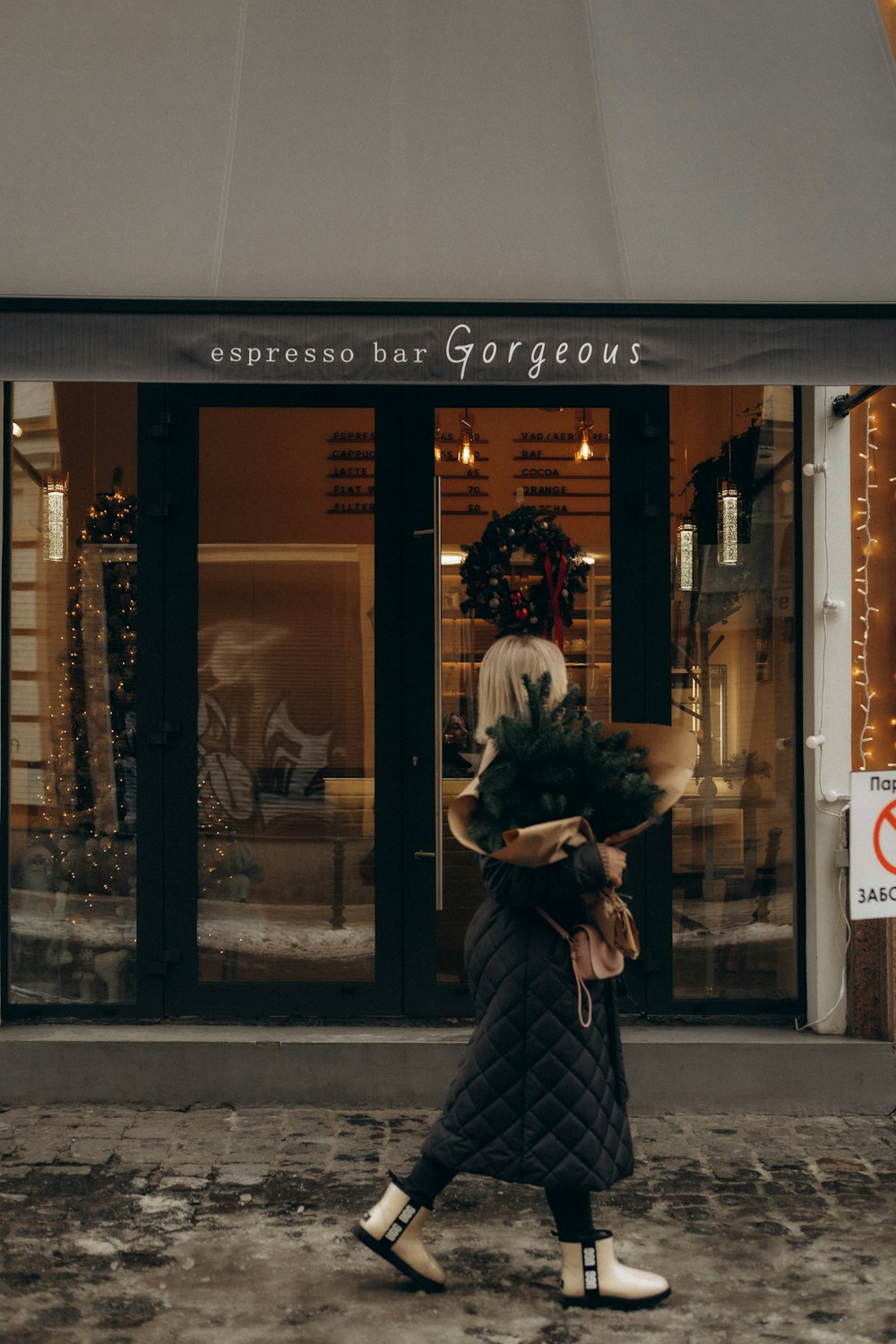 a woman walking down a street past a store front
