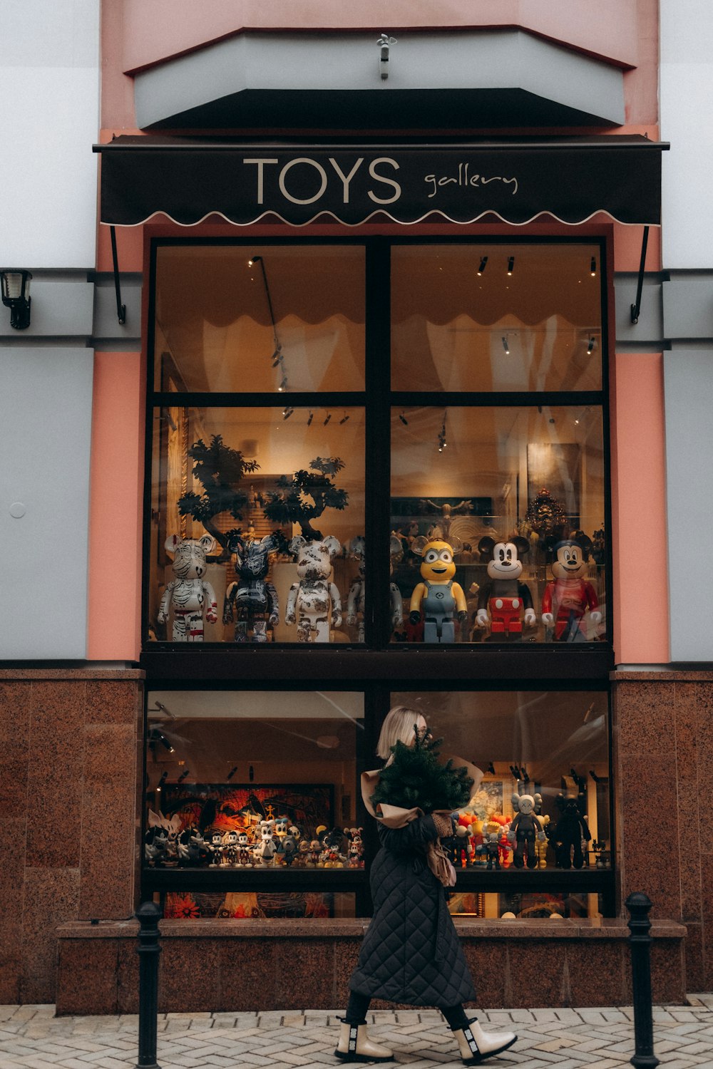 a woman walking past a store front with stuffed animals