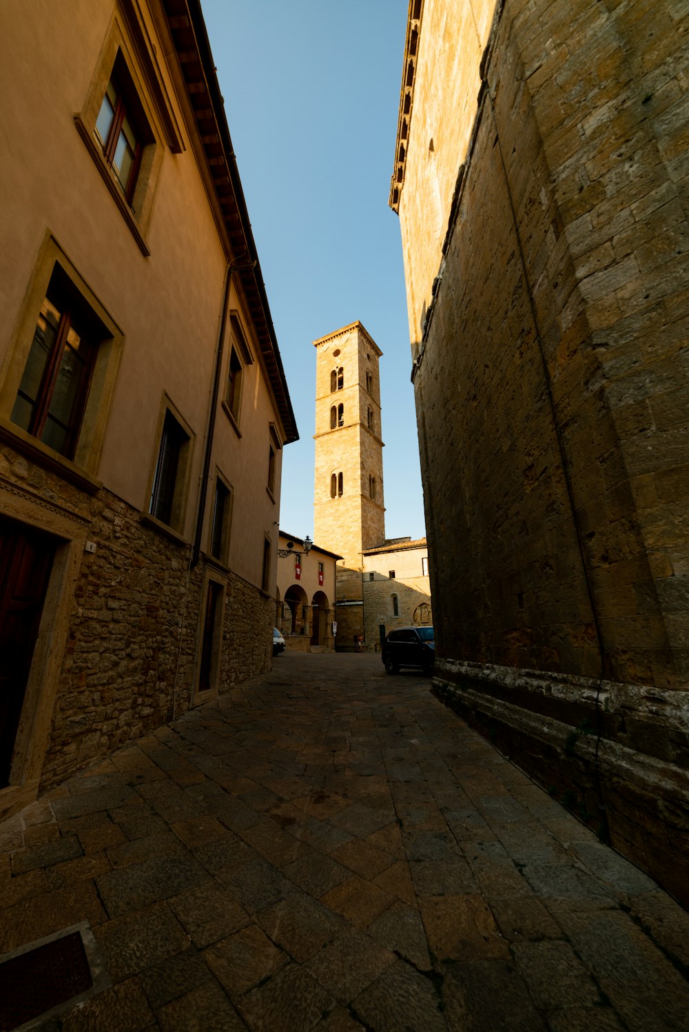 a narrow street with a tall tower in the background