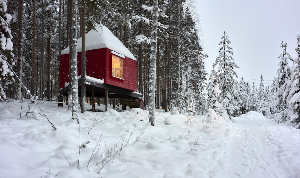 a red cabin in the middle of a snowy forest